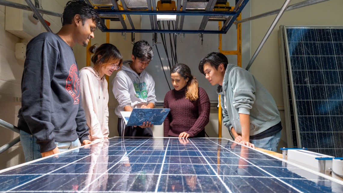 University students learning about solar panels during an outdoor sustainability workshop